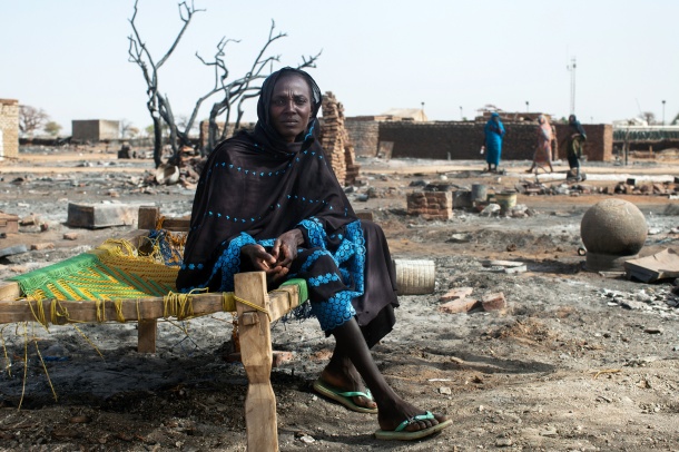 A displaced woman sits on a bed next to the remnants of her burnt house in Khor Abeche, South Darfur. April, 2014. Photo: Albert Gonzalez Farran, UNAMID (CC 2.0)