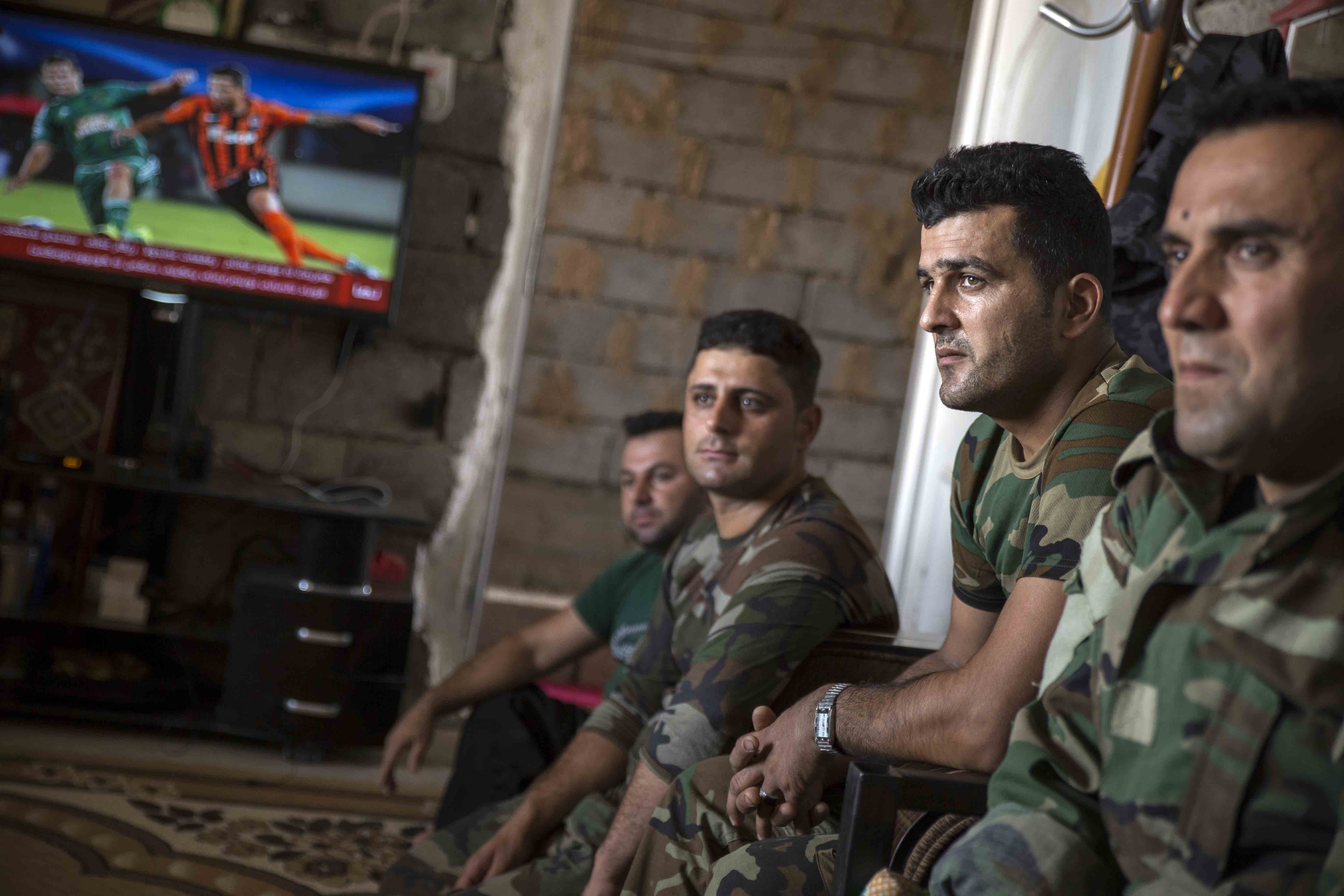 Peshmerga fighters listen to their commander. The house where they sit was captured from Islamic State and is now used as a Peshmerga base.